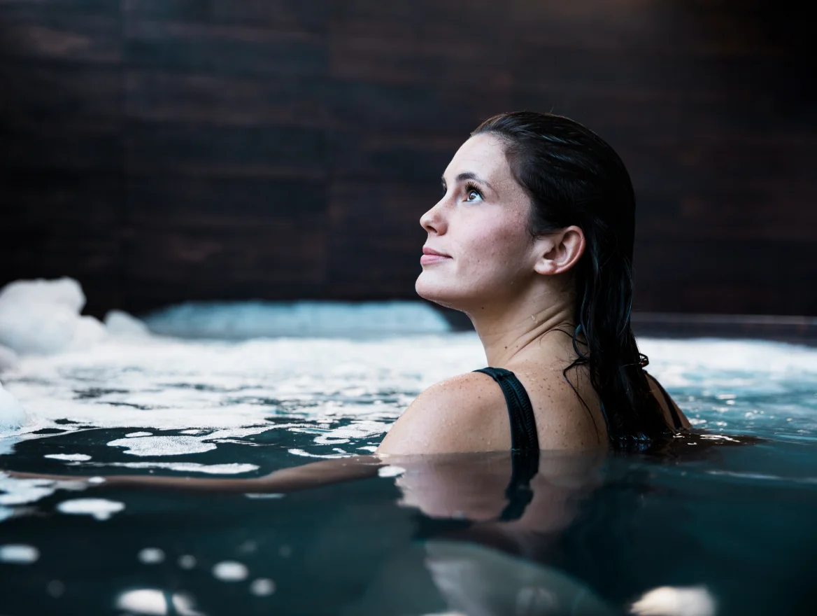 A woman resting in a warm hydrotherapy pool, looking upward